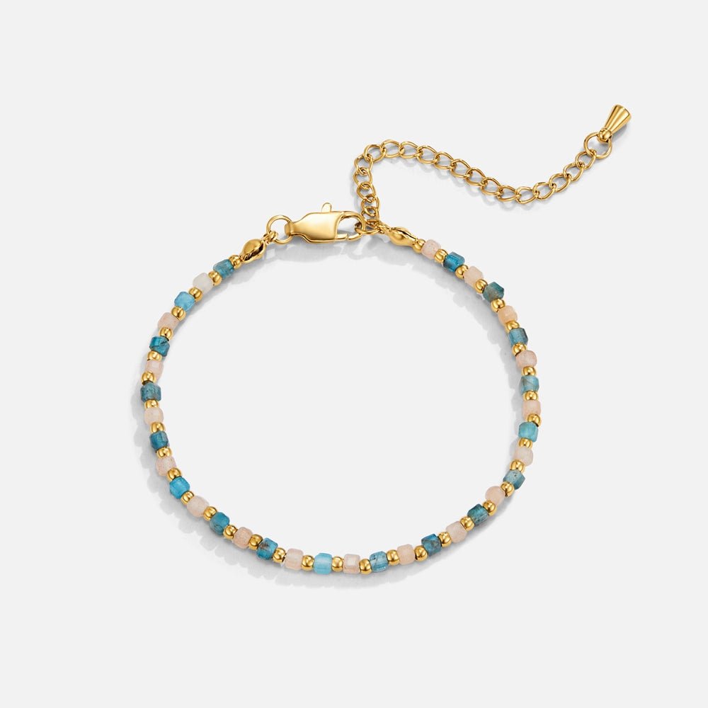 Alashan Blue Bead Bracelet, laid flat on a pale background, blue and pink beads with gold accents