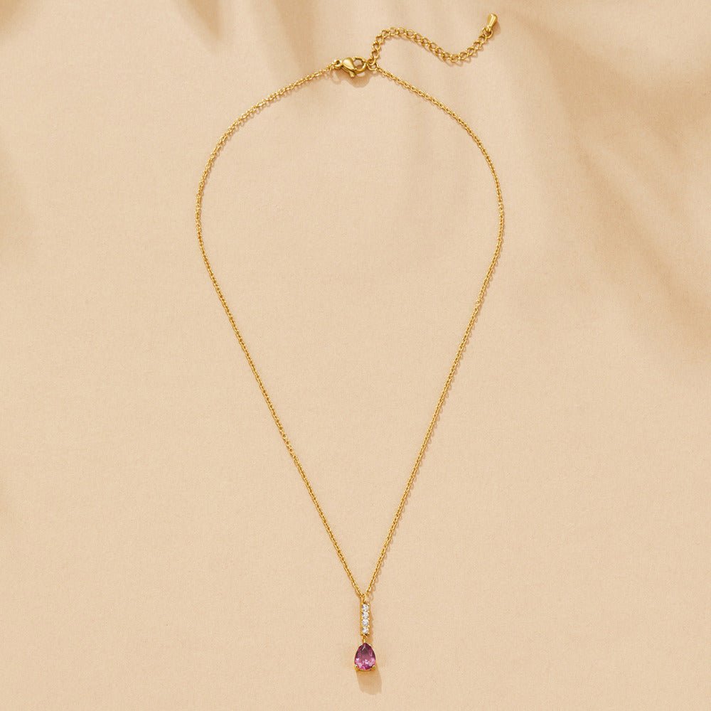 Crystal Pink Teardrop Necklace, laid flat on beige fabric, gold chain with pink teardrop pendant