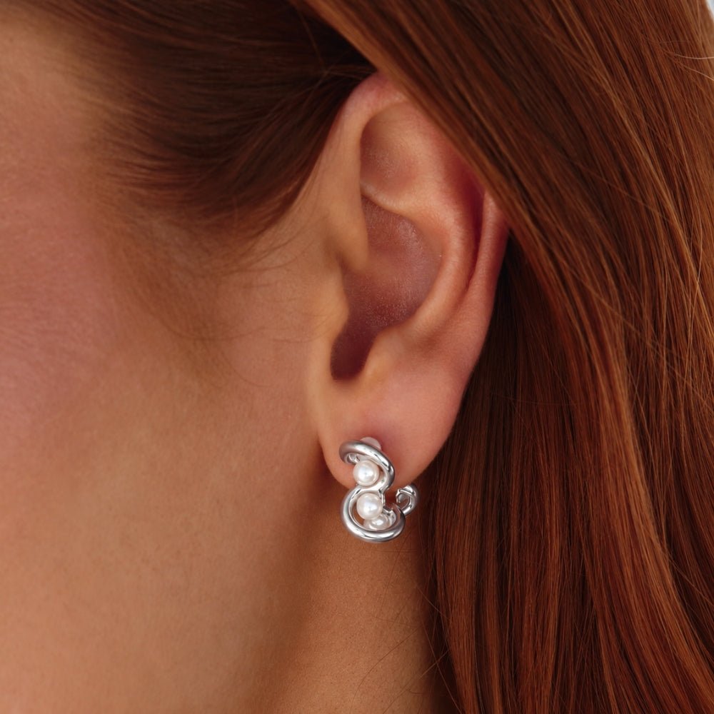 Tara Silver Entwined Pearl Earrings, worn on an ear, silver loops with small white pearls
